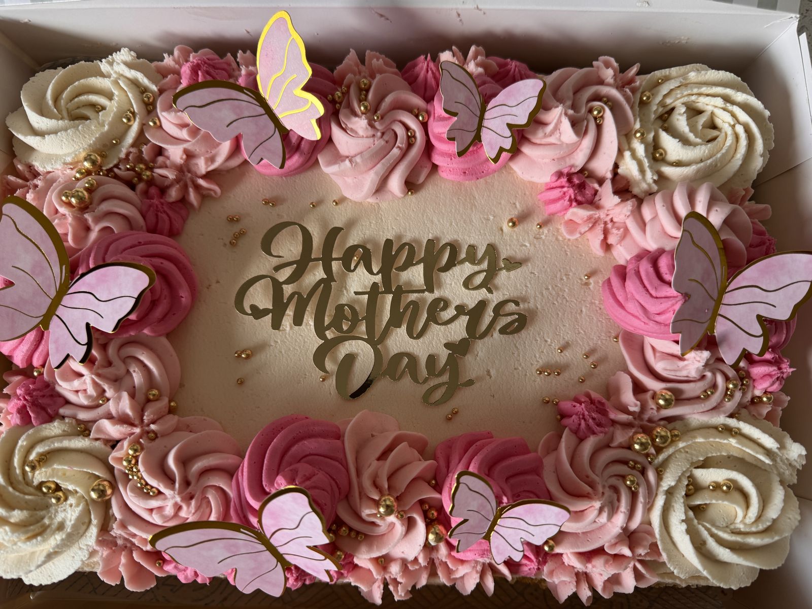A decorated traybake cake with buttercream roses and a piped message
